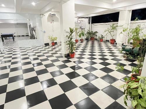 a room with a black and white checkered floor with plants at Apna Homes Stay & Hotel I Gurugram I Sector-71 in Gurgaon