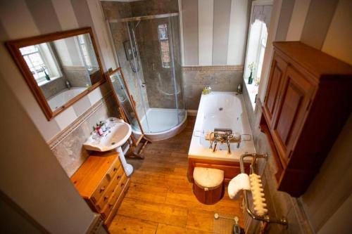 a bathroom with a tub and a shower and a sink at Burtree Country House, Tipi's, Treehouse & Lodge & house rooms with hot tubs in a private garden in Thirsk