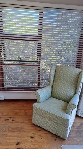 a chair sitting in front of a large window at Martha's Place in Gordonʼs Bay