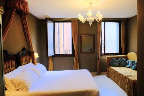 a bedroom with two beds and a chandelier and windows at H O T E L S A N G A L L O l in Venice