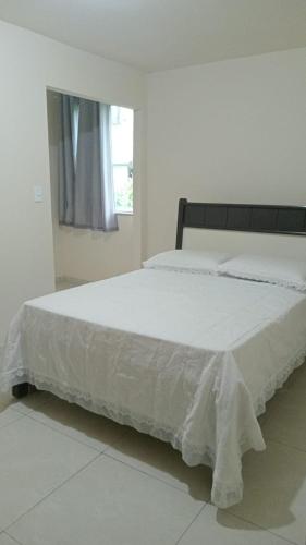 a bedroom with a large white bed with a window at Refúgio da Light in Carmo