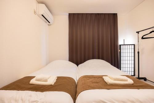 a bedroom with two beds with towels on them at Kawagoe Good Place House in Kawagoe