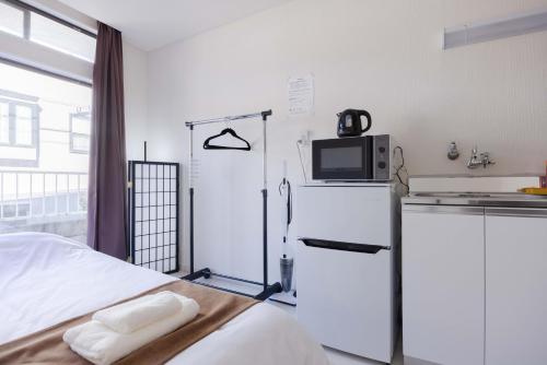 a small kitchen with a refrigerator and a microwave at Kawagoe Good Place House in Kawagoe