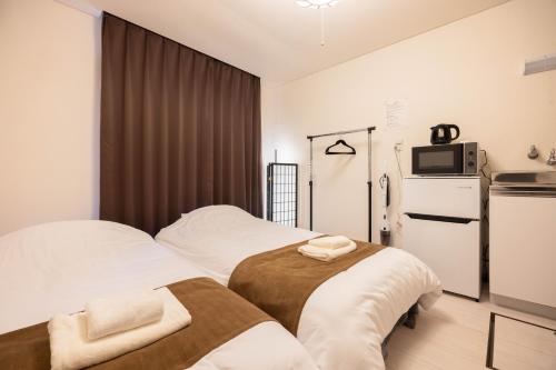 a bedroom with two beds and a refrigerator at Kawagoe Good Place House in Kawagoe