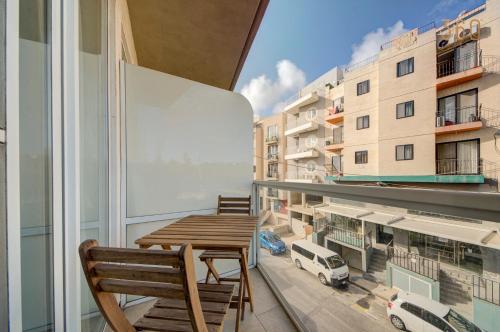 a balcony with a wooden table and chairs on a building at Lovely homey 1BR Apt in Msida close to Valletta by 360 Estates in Tal-Ħriereb