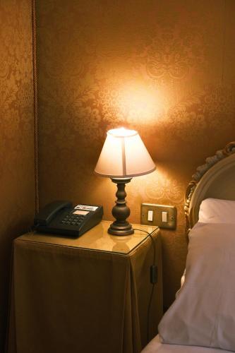 a lamp and a phone on a table next to a bed at H O T E L S A N G A L L O l in Venice