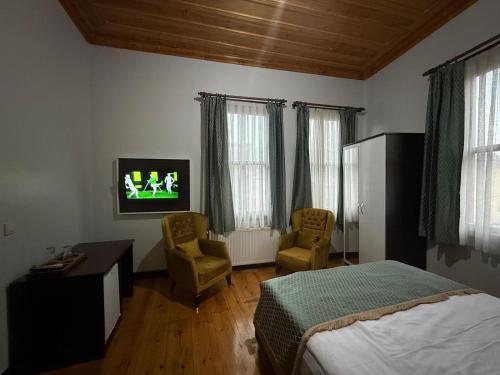 a bedroom with a bed and a tv and two chairs at Grand Bedir in Istanbul