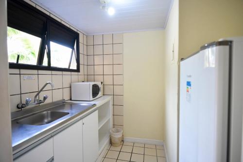 a small kitchen with a sink and a refrigerator at Morro do Sol Hotel & Eventos in Porto Belo