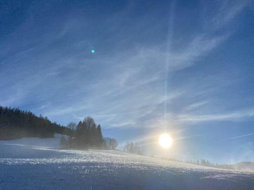 a snow covered slope with the sun in the sky at Hörlbauer-Leogang in Leogang