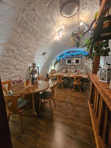 a restaurant with wooden tables and chairs and a stone wall at Pension & Gasthof "Am Park" UG in Stützerbach