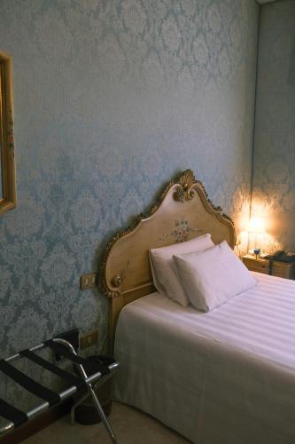 a bedroom with a bed with white sheets and blue wallpaper at H O T E L S A N G A L L O l in Venice