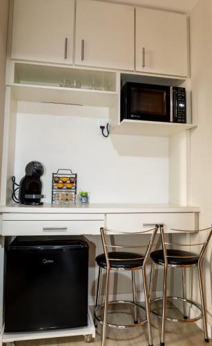 a kitchen with a counter with two chairs and a microwave at Flat Hotel Congonhas in Sao Paulo
