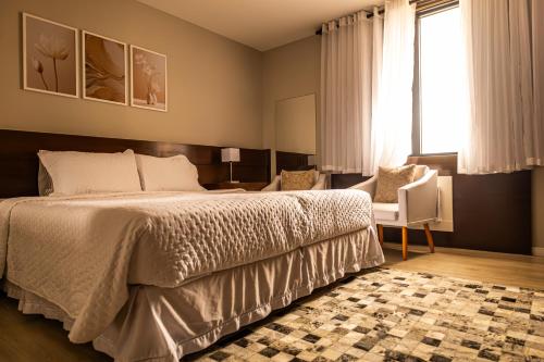 a bedroom with a bed and a chair and a window at Flat Hotel Congonhas in Sao Paulo