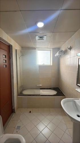 a bathroom with a toilet and a sink and a window at Clifton International Hotel in Fujairah