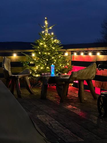 a christmas tree on a wooden table with a candle at Burtree Country House, Tipi's, Treehouse & Lodge & house rooms with hot tubs in a private garden in Thirsk