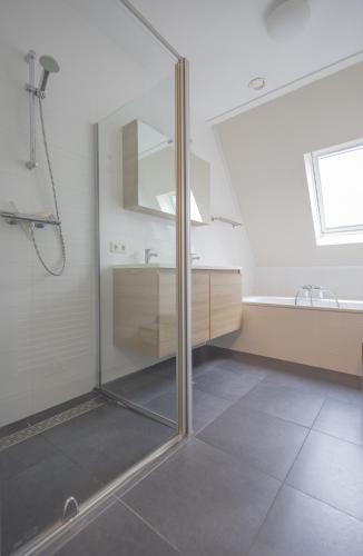 a bathroom with a glass shower and a sink at Duinhof II 21 in Cadzand
