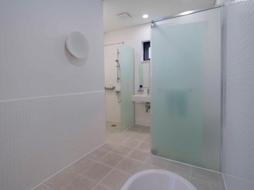 a bathroom with a toilet and a glass shower stall at Boutique Pool Villa NAMIB in Jeju