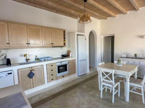 a kitchen with a table and a white refrigerator at White Rock Suites & Villas in Houlakia