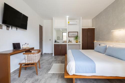 a hotel room with a bed and a desk and a television at Areia Playa del Carmen - Beach Front Hotel in Playa del Carmen
