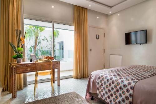 a bedroom with a desk and a bed and a window at Riad Zyo in Rabat