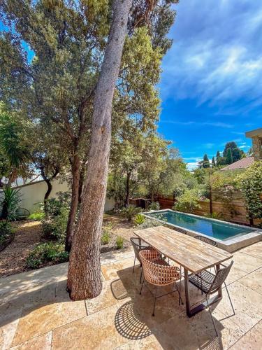 une table et des chaises assises à côté d'un arbre dans l'établissement Villa Rethel avec piscine - dans le centre de Montpellier, à Montpellier