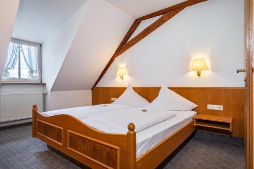 a bedroom with a wooden bed with white sheets at Gasthof Adler in Ebenweiler