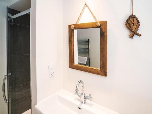 ein Badezimmer mit Waschbecken und Spiegel an der Wand in der Unterkunft Cannon Corner by The Suffolk Cottage Collection in Aldeburgh