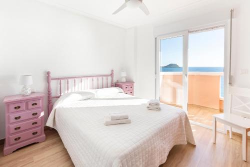 a white bedroom with a bed and a window at Apartamentos Turisticos Isla Grosa in La Manga del Mar Menor
