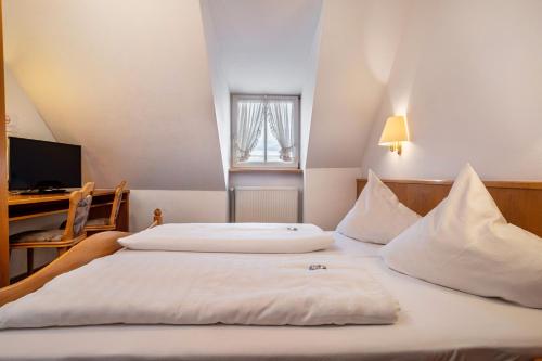 two beds in a hotel room with a desk at Gasthof Adler in Ebenweiler