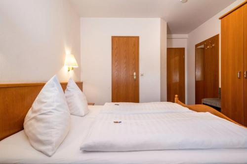 a bedroom with a white bed with white pillows at Gasthof Adler in Ebenweiler