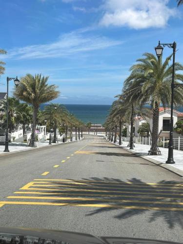 an empty street with palm trees and the ocean at KB Villas 58 in Bình Sum