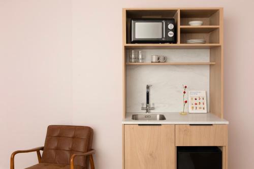 a kitchen with a sink and a microwave and a chair at Bob W London Holland Park in London