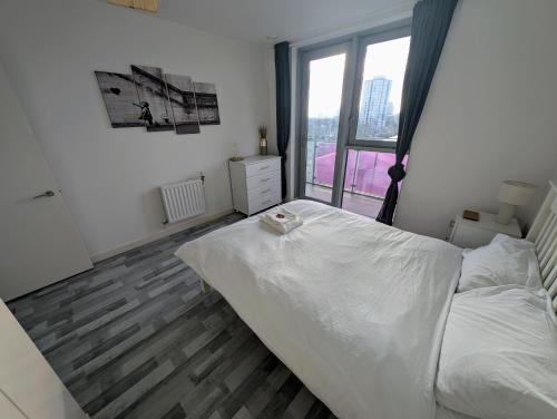 a bedroom with a white bed and a large window at GioGio - Comfortable Stratford Flat with Stunning Views in London