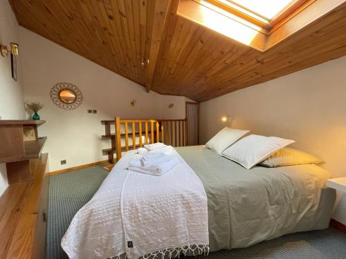une chambre avec un grand lit avec un plafond en bois dans l'établissement Maison de ville idéalement située à Châtel-Guyon, à Châtel-Guyon