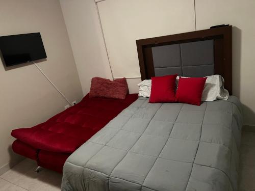 a bedroom with a large bed with red pillows at Alojamiento residencial, cerca de TSM in Torreón
