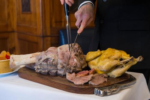 a person cutting a piece of meat on a cutting board at Bettoja Hotel Mediterraneo in Rome