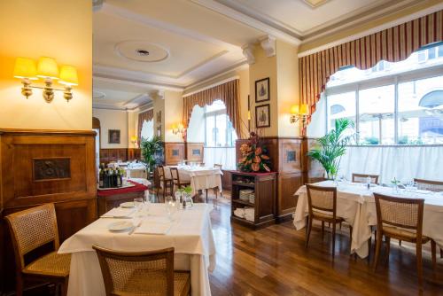 a restaurant with white tables and chairs and windows at Bettoja Hotel Mediterraneo in Rome