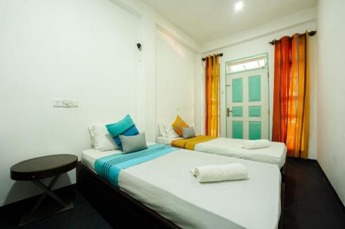 a bedroom with two beds and a table and a window at ceylonza in Kamburugamuwa