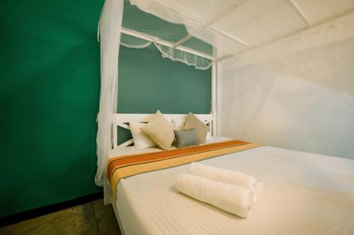 a bedroom with a white bed with a green wall at ceylonza in Kamburugamuwa