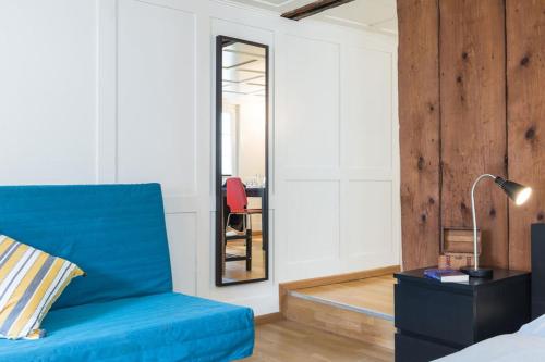 a living room with a blue couch and a mirror at HITrental Zeughausgasse - Apartment in Zug
