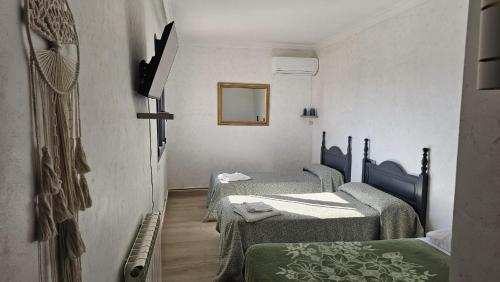a room with three beds and a mirror at Hotel Restaurante EL PATAS in Corral de Almaguer