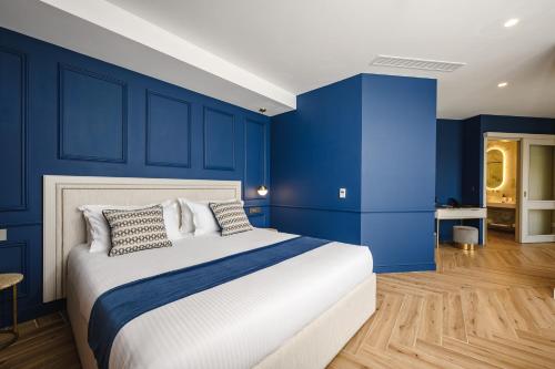 a bedroom with blue walls and a bed with pillows at XVI Suites - Adults Only in Naxxar