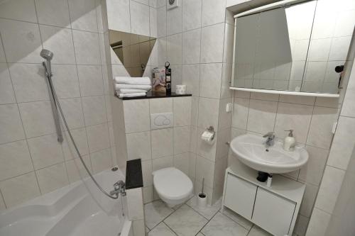 a white bathroom with a sink and a toilet at City Apartment 1 in Brühl