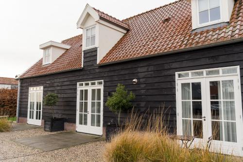 a house with black siding and white doors at Hof Olmenstein in Goes