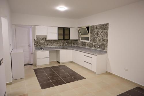 cocina con armarios blancos y suelo de baldosa marrón en Go Egypt Apartments Inside Karma Beach Resort North Al Ahiaa , Hurghada, en Hurghada