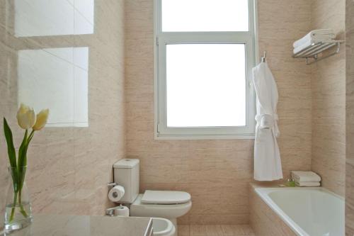 a bathroom with a toilet and a window and a sink at NH City Buenos Aires in Buenos Aires