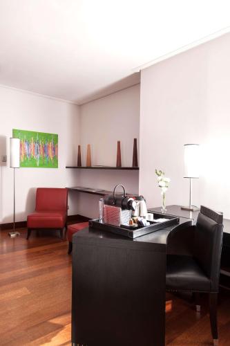 a living room with a table and a red chair at NH City Buenos Aires in Buenos Aires