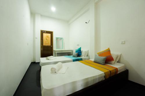 two beds in a white room with a mirror at ceylonza in Kamburugamuwa