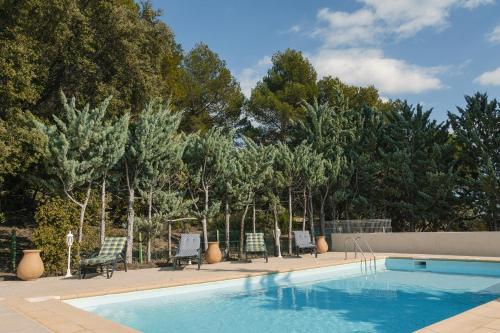 une piscine avec des chaises et des arbres en arrière-plan dans l'établissement Villa du Saignadou, à Tourtour