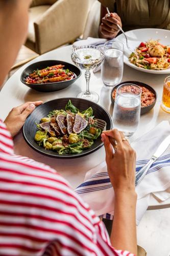 a woman sitting at a table with a plate of food at Viceroy Chicago in Chicago